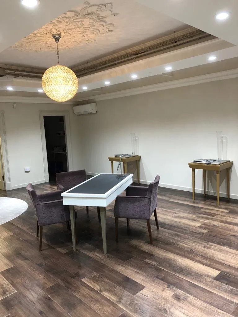 Spacious room with LVT floors, a table and four chairs at the center. Decorative ceiling with a round pendant light adds warmth and elegance.