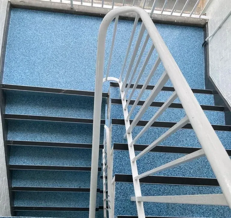 A staircase with blue speckled steps and a white railing, viewed from above. The clean, modern design creates a calm, orderly atmosphere.