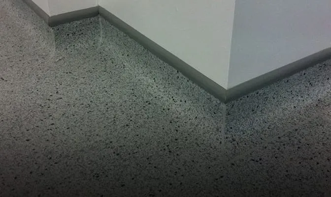 Speckled gray flooring appears to curve up seamlessly into the white walls, creating an optical illusion of a smooth, continuous surface.